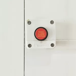 A red panic alarm switch mounted on a clean white wall, emphasizing safety measures indoors.