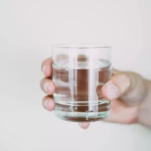 A close-up shot of a hand holding a clear glass of water, symbolizing refreshment.